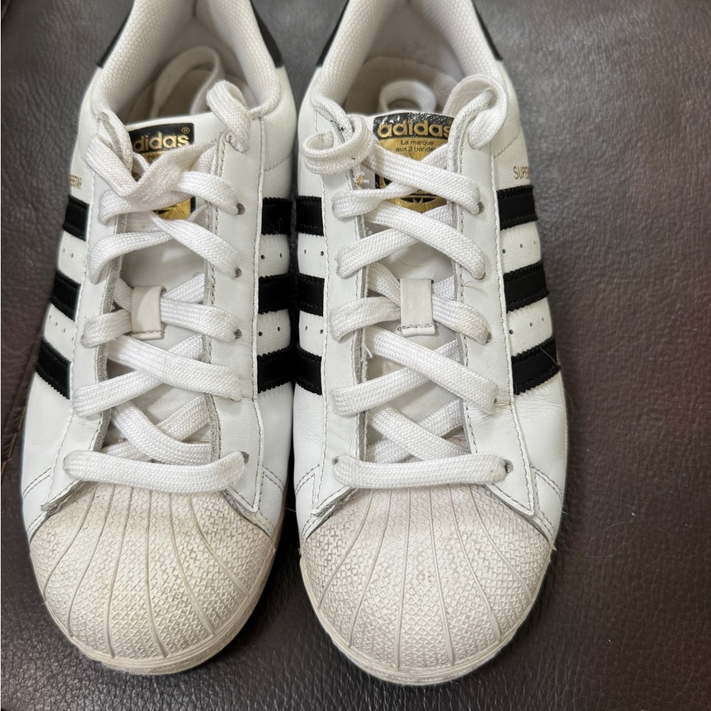 Adidas superstars White Sneakers with black stripes.